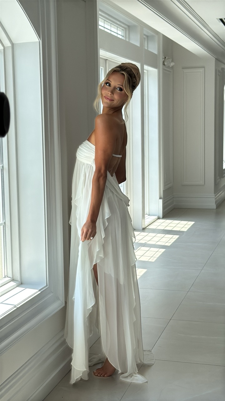 Bride wearing a flowing strapless white wedding gown poses beside sunlit windows at Florentine Gardens in River Vale, New Jersey, before her wedding ceremony.